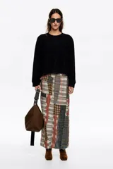 Jersey de lana color negro, de corte boxy y diseño holgado, con escote redondo, manga larga recta y bolsillos de plastrón en el pecho.