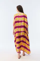 Kaftan maxi amplio de color amarillo, con escote redondo, mangas cortas y ruedo irregular. Presenta un diseño estampado a cuadros con efecto teñido.