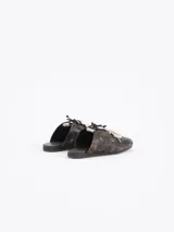 Zapatilla tipo mule (sin talón) de cuero vacuno, color celeste con efecto gastado y detalles de recortes. Presenta un logo estilizado en el lateral y cordones anchos de color beige y marrón.