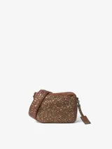 Bolso bandolera pequeño de cuero vacuno lavado, color marrón, con tachas metálicas en la parte frontal. Cuenta con cierre de cremallera, asa de hombro extraíble, bandolera regulable y extraíble, bolsillos internos y forro de algodón.