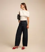 Blusa color crema confeccionada en crepé, con escote asimétrico y una manga corta con drapeados.