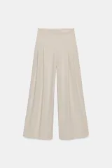 Pantalón de tiro medio color marrón, con pinzas en el delantero, perneras anchas de corte recto y trabillas para cinturón. Cuenta con bolsillos laterales y traseros, y cierre frontal con cremallera y botón.