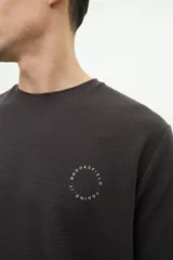 Remera de manga corta color gris oscuro, con textura de punto waffle y logo circular estampado en el pecho.