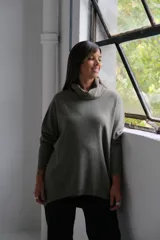 Polerón de punto color verde oliva, con cuello alto holgado, mangas largas con puños ajustados y diseño de corte amplio.