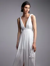 Mono largo blanco con escote en V, breteles finos con lazo y tajo lateral en la pierna.