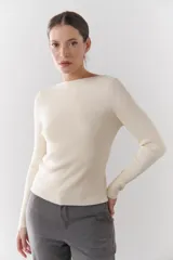 Buzo de morley color crema, con cuello bote y manga larga. Presenta un diseño de punto acanalado y un detalle de franja horizontal en el pecho.