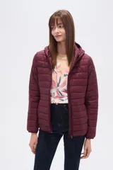 Campera acolchada tipo puffer, color beige claro, con capucha y cierre frontal. Presenta costuras horizontales y un calce entallado.