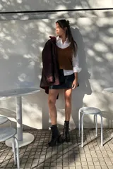 Minifalda negra de cuero sintético con corte campana y costuras decorativas en hilo blanco.