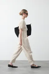 Pantalón baggy negro de silueta relajada con volumen amplio y caída fluida. Presenta detalles de ajuste con hebillas metálicas en el bajo y un cinturón de tela con hebilla metálica en la cintura.