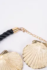 Set compuesto por un collar de cordón trenzado negro con dije central en forma de concha dorada y un par de aros a juego con diseño de concha dorada.