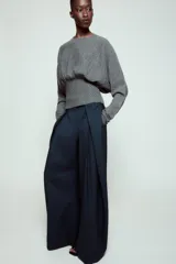 Jersey de punto color gris, con cuello redondo, manga larga y detalle de cintura ajustada con tejido tipo nido de abeja.