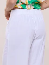 Pantalón crop de lino y rayón, con diseño wide leg de corte holgado, estampado tropical de hojas en tonos verde, azul y marrón sobre fondo blanco. Cuenta con pretina trasera elastizada y bolsillos delanteros.