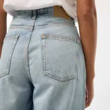 Pantalón de jean celeste de corte recto, tiro alto y con dobladillo ancho en el ruedo.