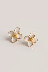 Aros tipo caravana con diseño de flor de cuatro pétalos en color blanco perlado y bordes dorados, con centro detallado en relieve dorado.