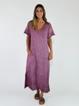Vestido midi de lino y algodón color lila, de corte holgado, con mangas cortas, escote en V, bolsillos laterales y aberturas en el dobladillo inferior.