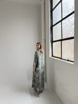 Vestido largo color verde militar con estampado floral, cuello drapeado y mangas largas de corte holgado.