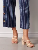 Pantalón de algodón estampado a rayas verticales azules y blancas, marca Erika. Tiene pretina elastizada, bolsillos delanteros, ruedo lateral con tajo y botones decorativos.