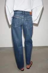 Jeans de mezclilla en color negro gastado, tiro bajo, corte de pernera recta y diseño clásico de cinco bolsillos con cierre frontal de cremallera y botón metálico.