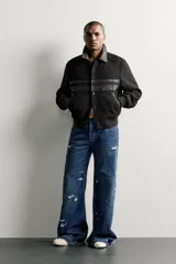 Cazadora cropped fit de color negro para hombre, con cuello solapa y detalles combinados en tejido efecto piel. Presenta mangas largas, bolsillos de doble vivo en la cadera, cierre frontal con botones a presión y puños y cintura elásticos ribeteados.