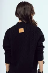 Sweater tejido negro de silueta relajada, con cuello alto y textura trenzada.