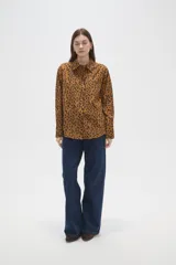 Camisa de algodón con estampado de manchas oscuras sobre fondo tostado, de corte holgado, manga larga, cuello clásico y cierre frontal con botones.