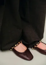 Zapato chatita de cuero sintético color marrón, con punta cuadrada, cordones decorativos en la capellada y una tira en el empeine adornada con tachas y argollas doradas.