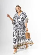 Maxi vestido blanco con estampado paisley en azul marino y detalles en tonos dorados, con cuello en V, mangas amplias y diseño escalonado.
