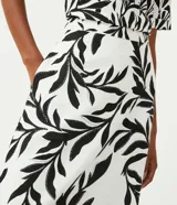 Pollera midi color blanco con estampado de hojas negras, cintura alta y corte recto.