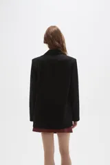 Blazer negro de corte clásico con cuello solapa, cierre frontal con botones y bolsillos laterales con solapa.