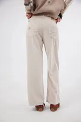 Pantalón de pana de corte ancho y tiro medio-bajo, con diseño de cinco bolsillos y acabado lavado. Presenta un aplique cuadrado decorativo en una de las piernas y un pin bordado de la marca.