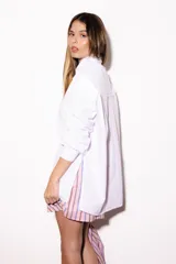 Camisa oversize a rayas celestes y blancas, con cuello camisero, manga larga y hilera de botones dorados metálicos.