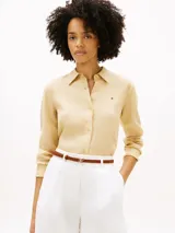 Camisa de lino puro color beige, de corte amplio y mangas largas, con cuello inglés, cierre frontal de botones y logo bordado en el pecho. Marca Tommy Hilfiger.