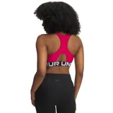 Top deportivo Under Armour de soporte medio, color fucsia con banda elástica inferior negra con el logo de la marca en blanco. Presenta diseño de espalda cruzada y tejido técnico de secado rápido.