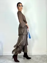 Vestido largo de seda italiana color chocolate, con escote en V, mangas largas abullonadas y diseño de falda con volados escalonados.