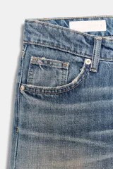 Jeans de tiro bajo y cinco bolsillos, con diseño de pierna ancha y larga. Presenta roturas y desgastes sutiles en la parte delantera. Cierre frontal con cremallera y botón metálico.