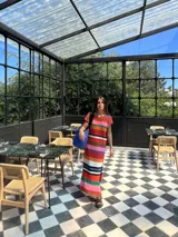 Vestido largo de tejido de punto, con rayas horizontales en tonos tierra, azul y blanco. Presenta cuello redondo, mangas cortas caídas y aberturas laterales en el ruedo.