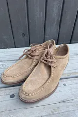 Zapato tipo mocasín acordonado de estilo derby, confeccionado en cuero nobuk color tostado, con costuras visibles y cordones al tono.