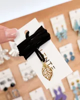 Choker de tiento negro con dije de hoja calada dorada.