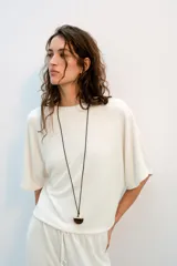 Top blanco de tejido rústico, con cuello redondo y mangas cortas amplias. Bajo recto.