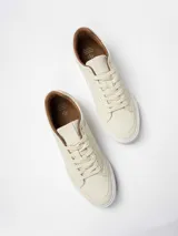 Championes urbanos de diseño minimalista en color beige, con suela de goma blanca y detalles en color marrón en el interior y borde del cuello.