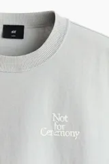 Remera de algodón en punto pesado, color verde menta, con cuello redondo acanalado, hombros caídos y diseño estampado en el pecho con la frase 'Not for Ceremony'.