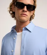 Camisa de manga larga color celeste, de corte slim, con cuello inglés y cierre frontal de botones.