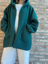 Campera de corderito color verde oscuro, con diseño holgado, cuello alto y manga larga. Presenta una etiqueta de cuero sintético en la manga.