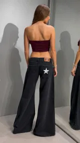 Jean de tiro bajo y corte wide leg en color negro lavado. Presenta una estrella blanca estampada en uno de los bolsillos traseros y una etiqueta de cuero con las iniciales AV en la cintura.