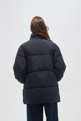 Campera puffer negra de corte holgado, con cuello alto, cierre frontal oculto y bolsillos laterales.