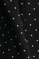 Vestido corto negro con estampado de lunares blancos, escote cuadrado, breteles anchos, cuerpo entallado y falda evasé con vuelo.