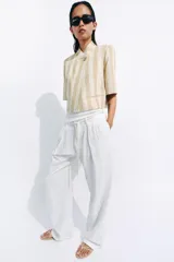 Blazer cropped de manga corta de Zara Woman Collection, confeccionado en hilatura con algodón, con diseño a rayas verticales en tonos beige y blanco. Cuenta con cuello subido, bolsillos de vivo en el delantero, forro interior y cierre frontal con botón.