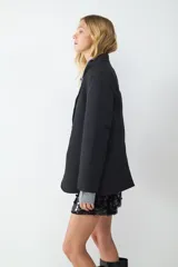 Blazer negro de corte recto y diseño oversize, con cuello de solapa, cierre frontal de dos botones y bolsillos con solapa en los laterales. Interior forrado.