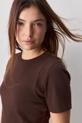 Remera blanca de manga corta y cuello redondo, con calce ajustado al cuerpo y diseño liso y minimalista.