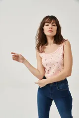 Musculosa rosa con estampado de margaritas blancas y amarillas, de bretel ancho, corte al cuerpo y cuello redondo.